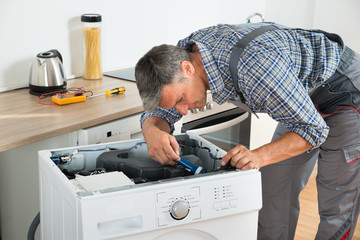 Handyman Checking Washing Machine With Flashlight