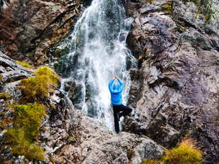 Obraz premium Young man in a yoga pose at the waterfall.