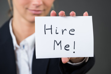 Midsection Of Businesswoman Showing Hire Me Card