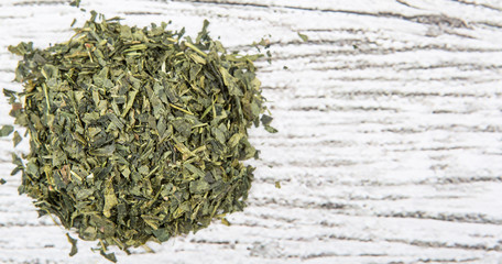 Fototapeta na wymiar Dried Japanese green tea leaves over wooden background