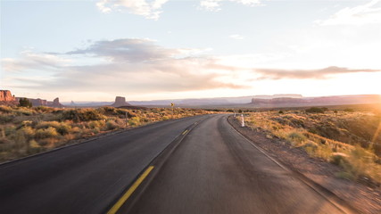 Driving USA: Sunset sunrise point of view shot along empty desert highway through Monument Valley, Arizona Utah - Powered by Adobe