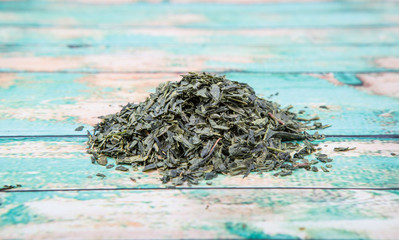 Dried Japanese green tea leaves over wooden background