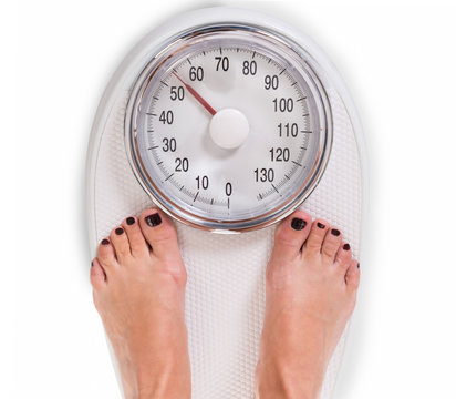 Woman's Legs On Weighing Scale Over White Background