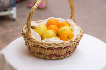 citrus fruits in a basket on a table in the street during the day. lemons and oranges in a basket made of twigs