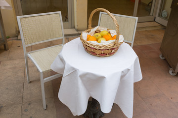 citrus fruits in a basket on a table in the street during the day. lemons and oranges in a basket made of twigs