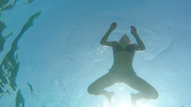 Man dives into the water in the sea and woman swims on the surface of the water above him