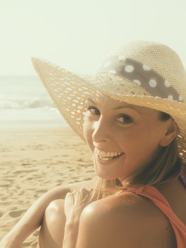 happy girl smiling portrait in the beach  wearing a  hat with the sea and horizon in the background
