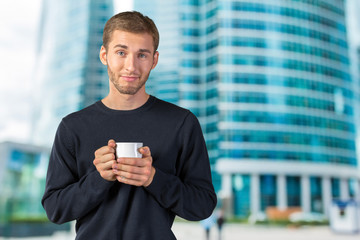 Fototapeta na wymiar Young handsome man holding warm cup of tea/coffee