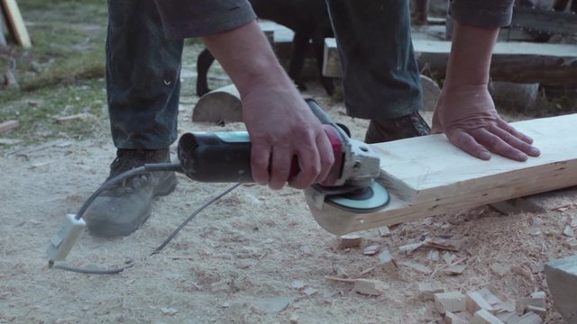     Carpenter carving fir timber using electric grinder;