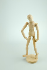 A wooden mannequin doll posing on white background
