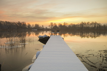 łódka zacumowana zimą do drewnianego pomostu