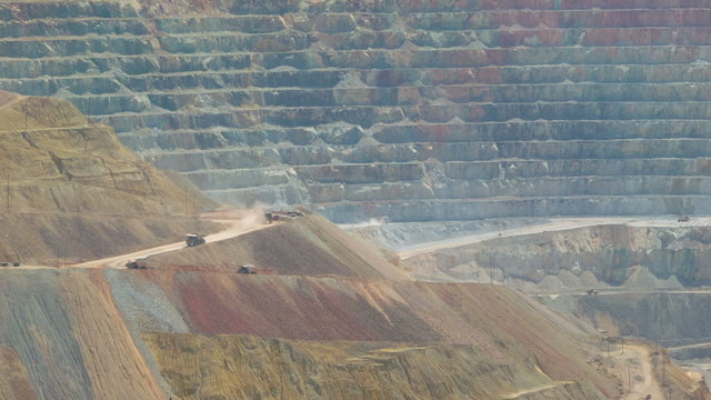 Telephoto live action shot of trucks in a large open cast copper mine metal pit in New Mexico, USA