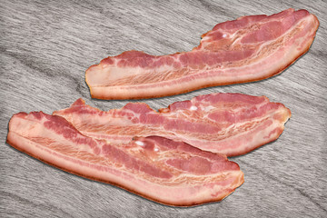 Pork Bacon Rashers on Bleached Wood Background