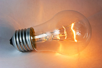 Glowing flashing light bulb lamp laying on white background