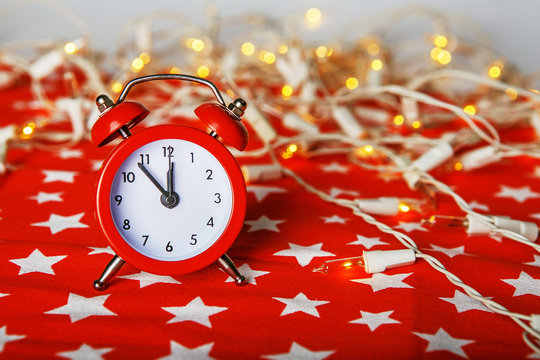 red alarm clock with lights bokeh on a red fabric background wit