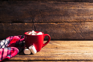red cup with cocoa and marshmallows on the wooden background