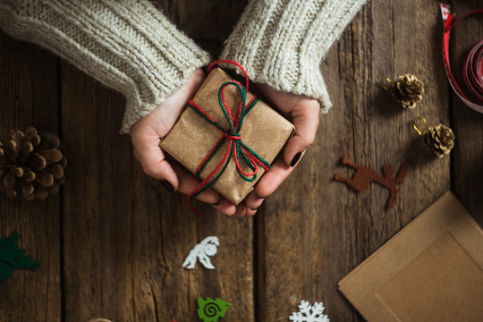 Male hands wrapping xmas gifts into paper and tying them up with red threads