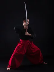 Foto auf Acrylglas Kampfkunst Young martial arts fighter with katana on black background