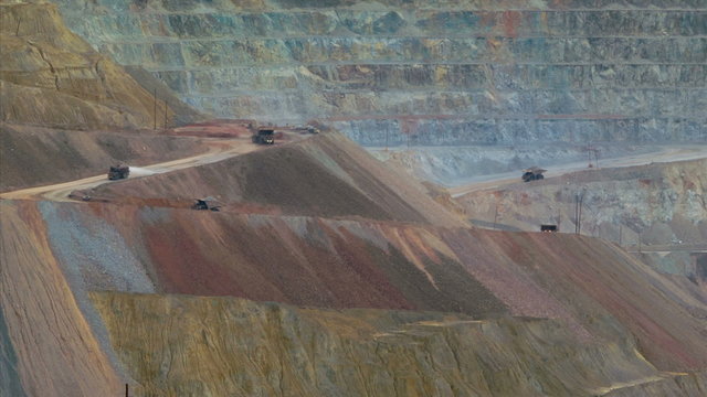 Time-lapse medium telephoto shot of tipper trucks in open cast quarry copper mine