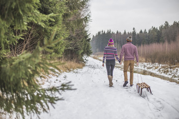 Young couple having a slaigh winter forest walk
