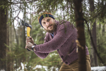 Young man is cutting christmas tree in the wood - 96334293