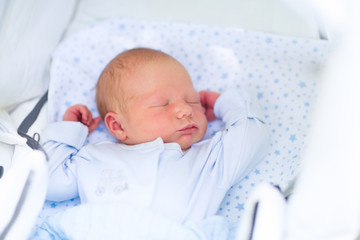 Newborn baby boy sleeping in white pram