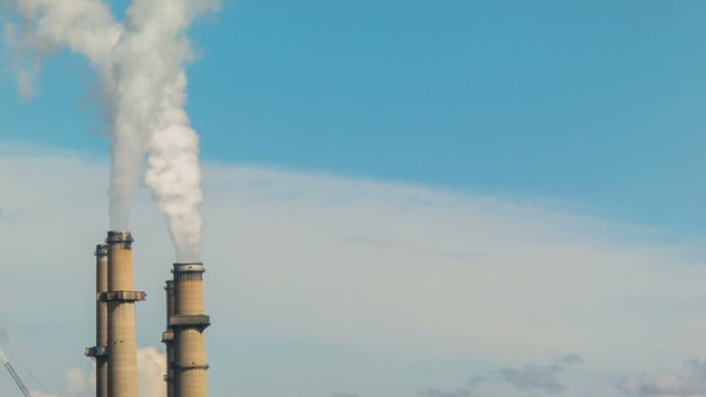 Telephoto shot of smoke emissions from electricity power plant generating station stacks  chimneys