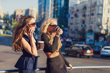 Lifestyle portrait of two best friends girls spending time in the center of the city at nice summer day, trendy fashion looks