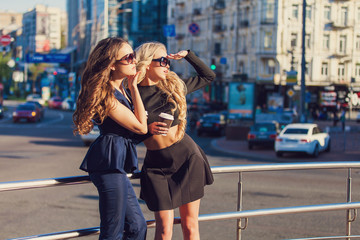 Lifestyle portrait of two best friends girls spending time in the center of the city at nice summer day, trendy fashion looks