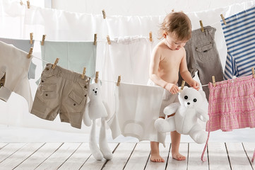 Little girl hangs laundry in the laundry - obrazy, fototapety, plakaty