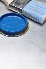 Blue paint can lid with brush on grey metal background