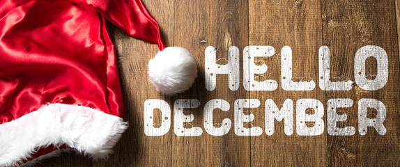 Hello December written on wooden background with Santa Hat - obrazy, fototapety, plakaty