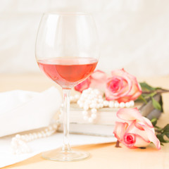 Glass of rose with vintage books and pearls