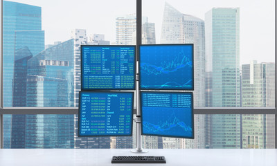 A modern trader's workplace or station which consists of four screens with financial data in a...