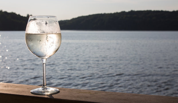 White wine spritzer on the wooden deck of a Canadian cottage sunset landscape