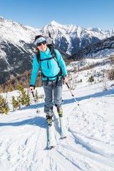 Fototapeta na wymiar Young woman ascending a slope on skis.