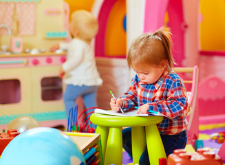 Fototapeta na wymiar cute little girl drawing with pencil in kindergarten