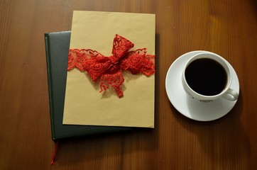 Cup of coffee on wooden table. Vintage books and pile of letters in the background