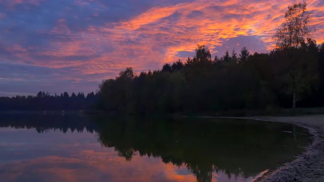 Colorful sunset over a calm lake in nature at the end of an autumn day.
