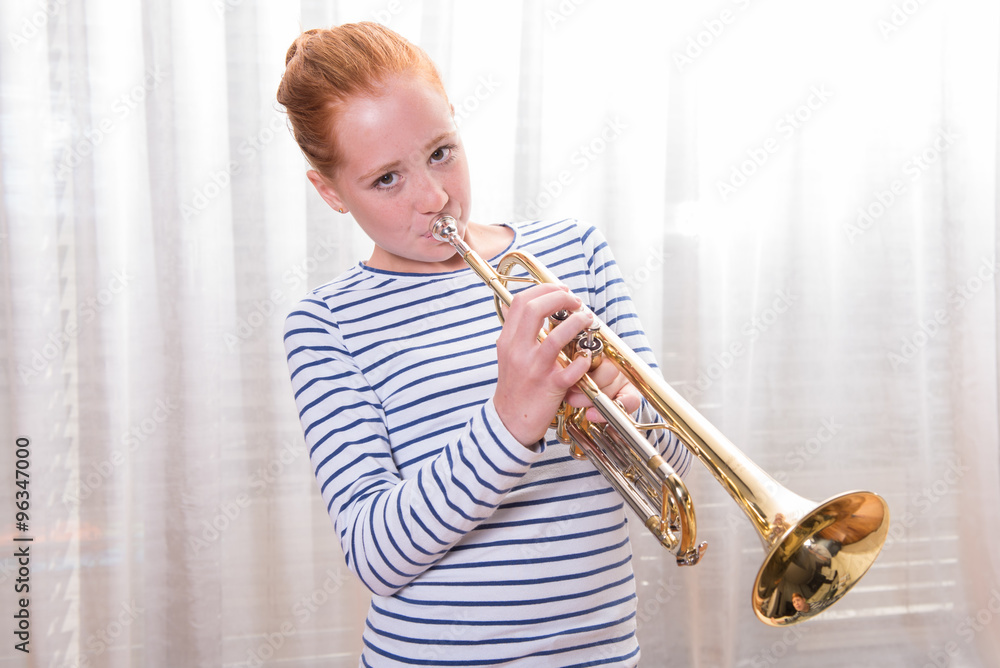 Wall mural red haired teenage girl playing the trumpet