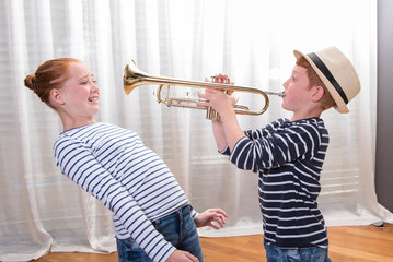 boy with hat is playing the trumpet - sister annoyed