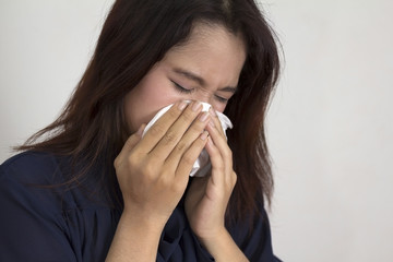 Concept of flu illness with Young woman holding tissue and runny nose