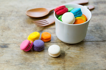 sweet macaroons in white cup on old wood table