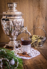 Tea in glass with coaster and russian samovar on wooden background. Home christmas decoration