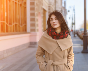 Young woman in a coat on the street. With sunshine effect.