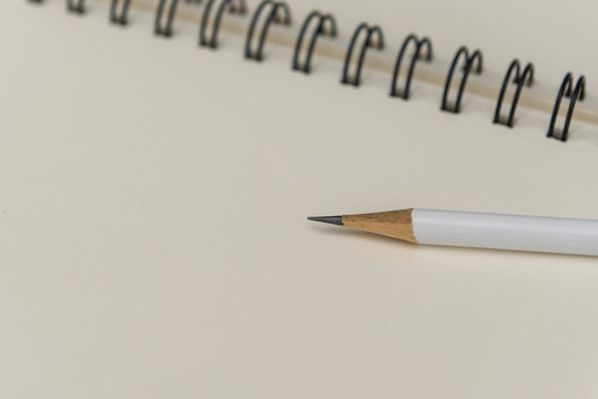 white pencil with blank notebook