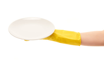 Close up of female hand in yellow protective rubber glove holding clean white plate against white background. Clipping path for plate border included.