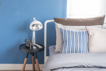 single white bed with white lamp and blue wall