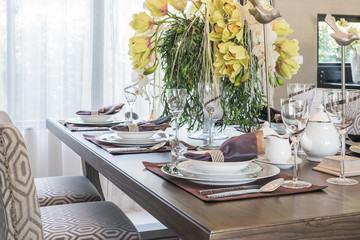 table setting on wooden dinning room with vase of flower