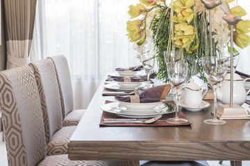 table setting on wooden dinning room with vase of flower